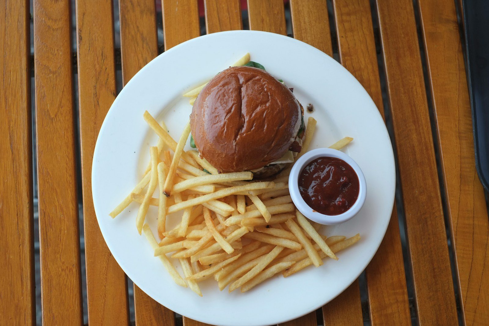 A burger and fries sit on a white plate.