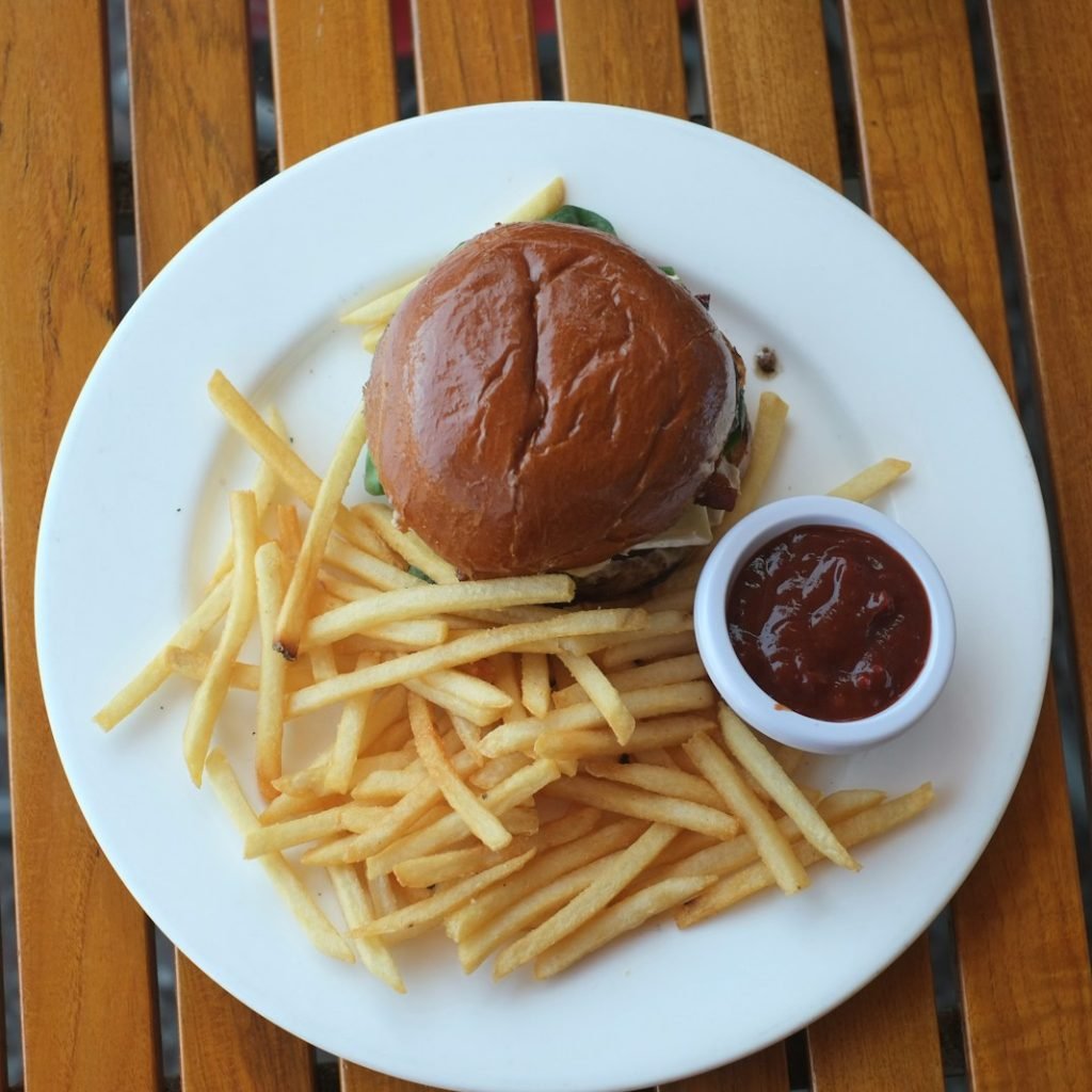 A burger and fries sit on a white plate.